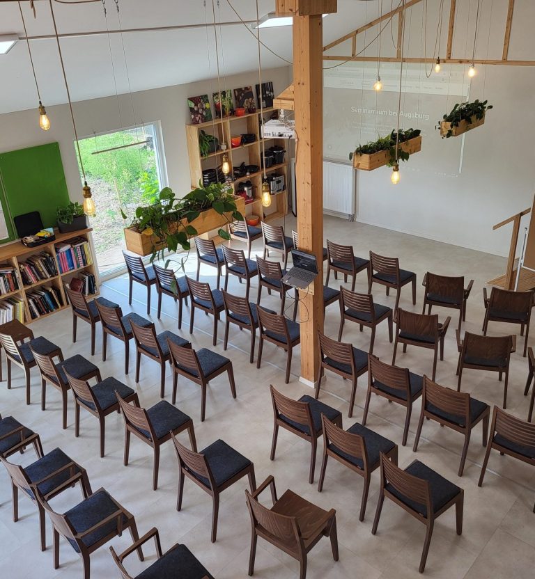 Moderne Seminar- oder Schulungsraum mit Holzstühlen und Pflanzen an der Wand.