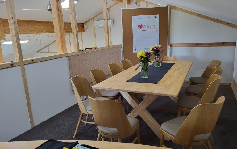 Moderne Besprechungsraum mit einem großen Tisch und Stühlen, dekoriert mit Blumen.
