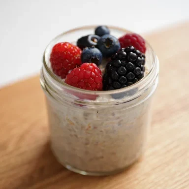 Haferbrei mit Himbeeren, Heidelbeeren und Brombeeren in einem Glas.