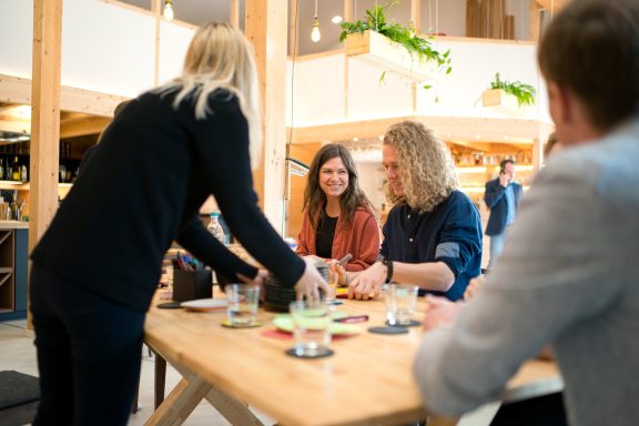 Personen am großen Holztisch