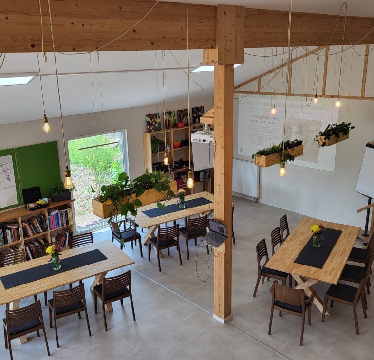 Helle, moderne Seminarräume mit Holztischen, Pflanzen und Holzelementen.