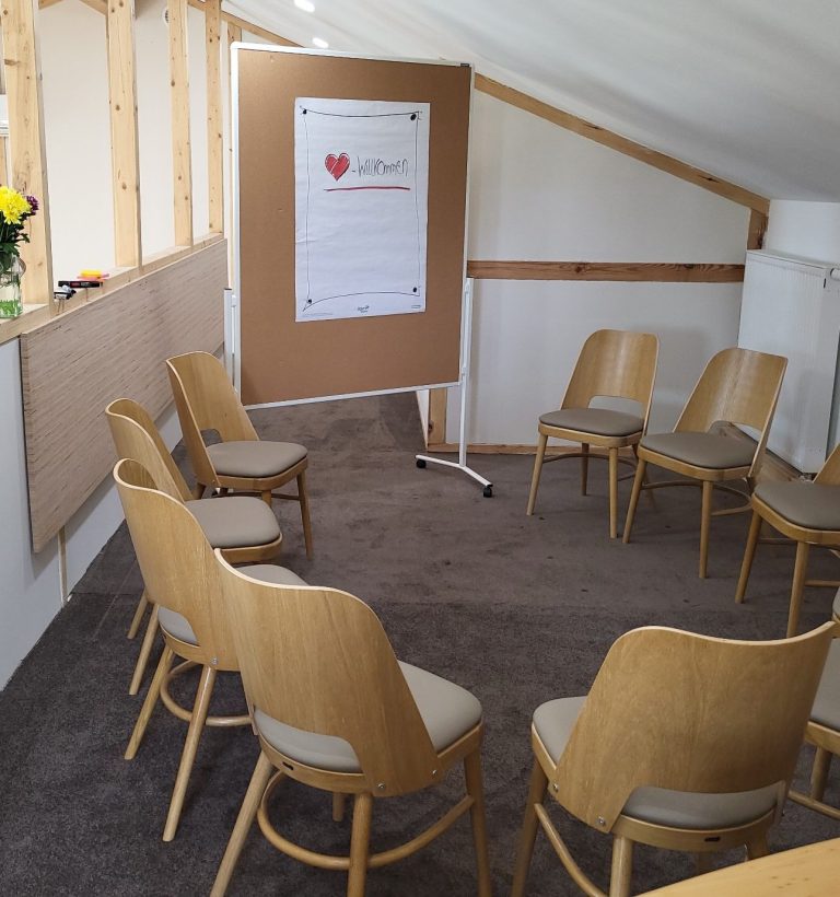 Leerer Besprechungsraum mit Holzstühlen und Flipchart auf einer Galerie.