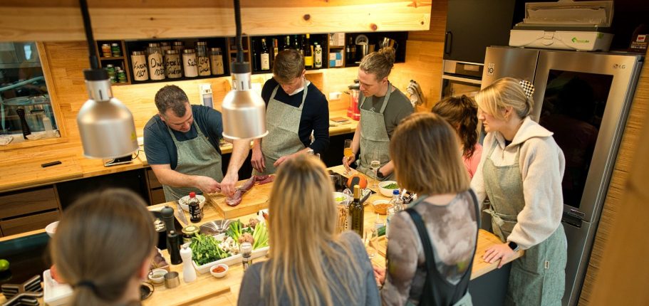 Gruppe von Menschen, die in einer modernen Küche gemeinsam Kochen lernen.