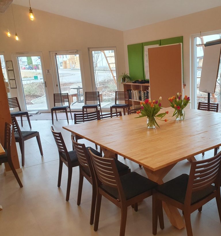 Besprechungsraum mit Holztafel, Stühlen und Blumen auf dem Tisch.